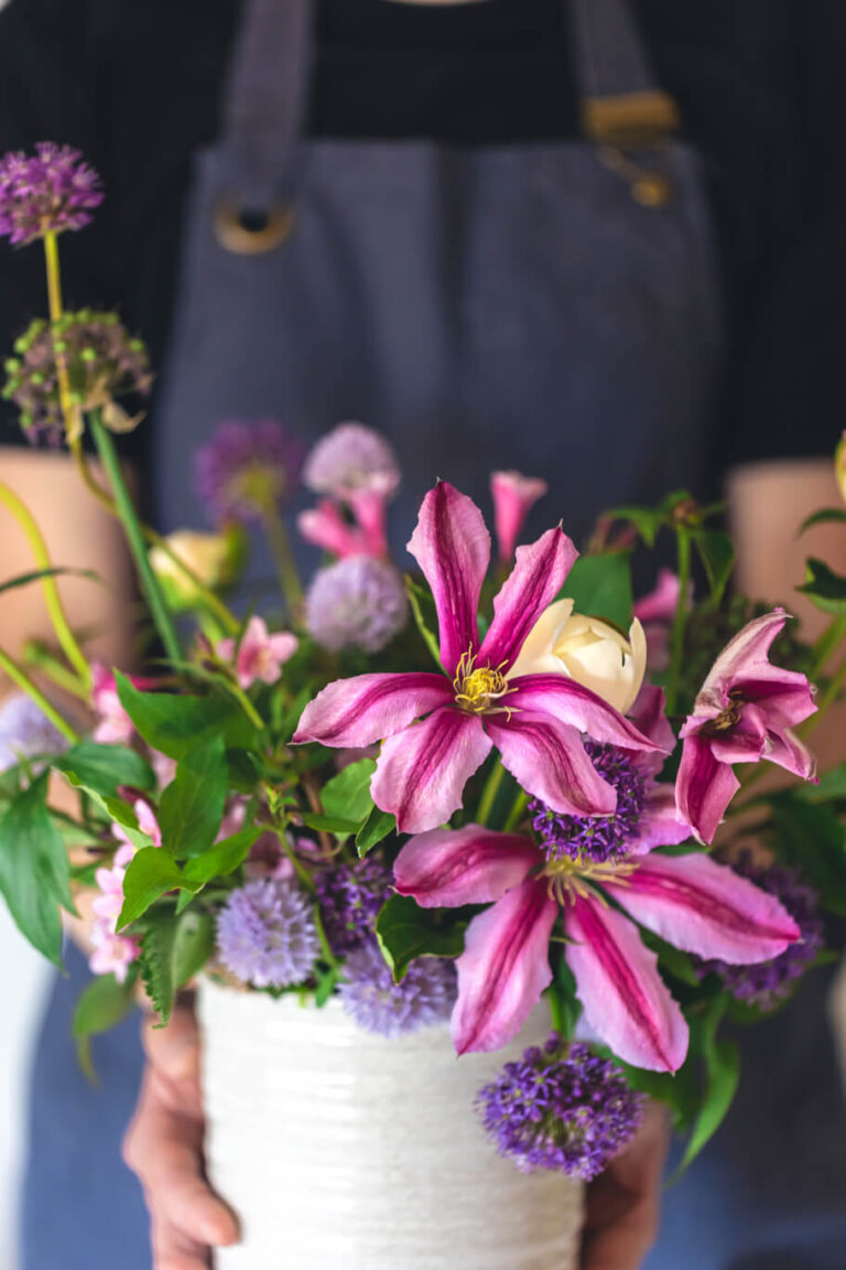 a-man-in-an-apron-holds-a-vase-of-flowers-close-u-2025-03-16-05-43-41-utc